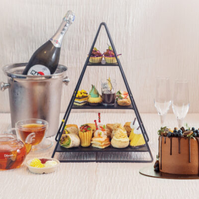 This image show case a tea party, featuring dilmah tea, chocolate cake, high tea set and more