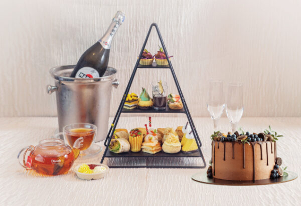 This image show case a tea party, featuring dilmah tea, chocolate cake, high tea set and more