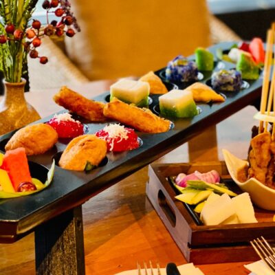 high tea set, with satay (grilled chicken) with sliced onion, nasi impit, cut fruits such as dragon fruit, watermelon, grapes and more. Enjoy Malay kuih on a congkak board