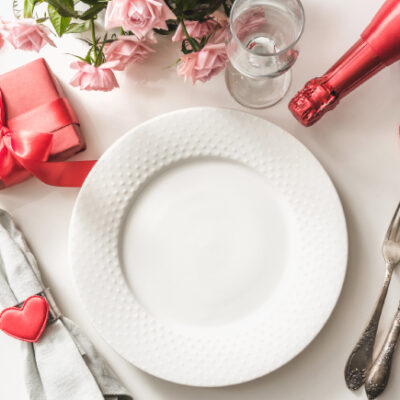 valentine's day set menu with white plate, wine, present box, cutlery, heart-shaped paper cutout