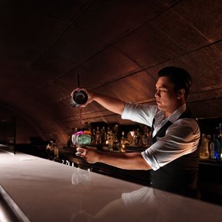 A mixologist is mixing a drink behind the bar counter.