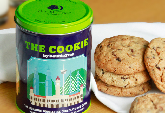 The photo shows a tin and a few pieces of DoubleTree signature chocolate chip cookies.