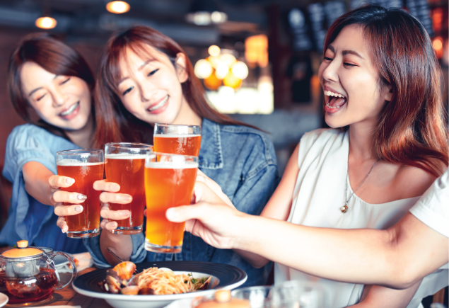 Four ladies are cheering with their glass of beers in their hand.