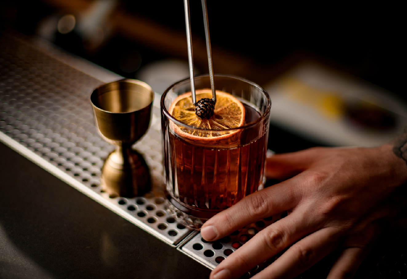 A bartender is decorating a glass of cocktail.