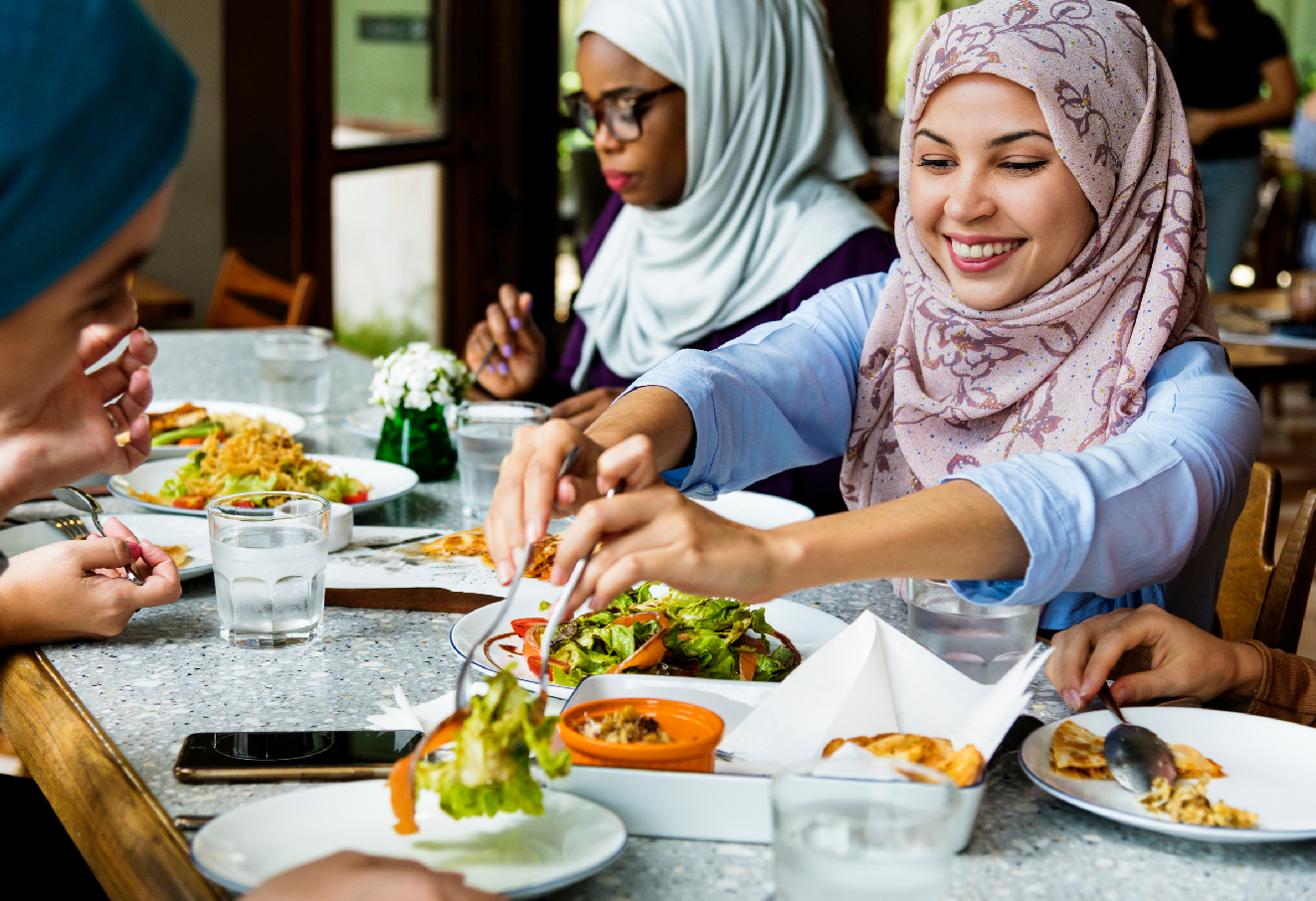 Three muslim girls are having lunch together.