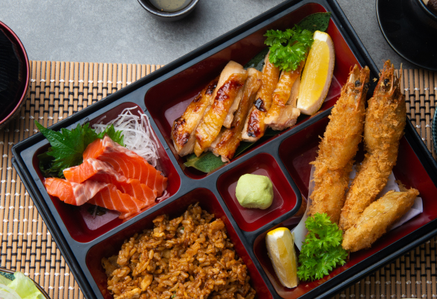 The photo shows a bento with salmon sashimi, chicken teriyaki, tempura, fried rice and wasabi.