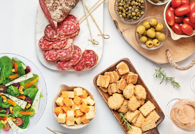 A variety of antipasti such as cold cuts, salad, cheese, olives, tomatoes and biscuits.