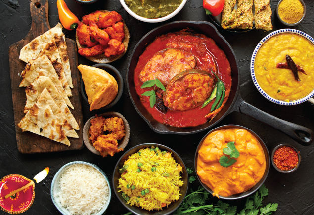 A variety of Indian food such as curry, briyani, pratha, white rice, daal and more on the table.