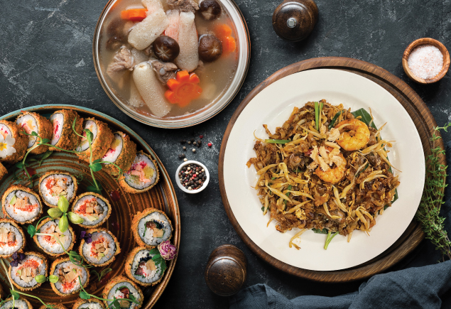 Three plates of delicious Asian cuisine such as sushi, herbal soup and char kuey teow are placed on top of a table.