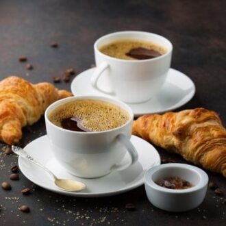 Two cups of hot coffee and two pieces of croissant.