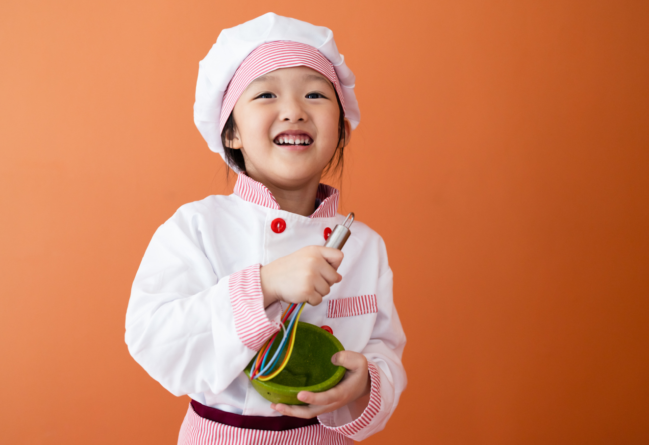 A little girl is dressed up in chef costume.