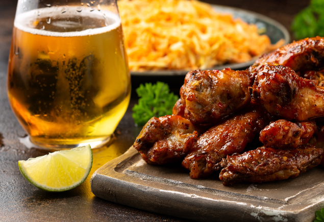 The photo shows a glass of beer, barbecued glazed chicken and spaghetti.