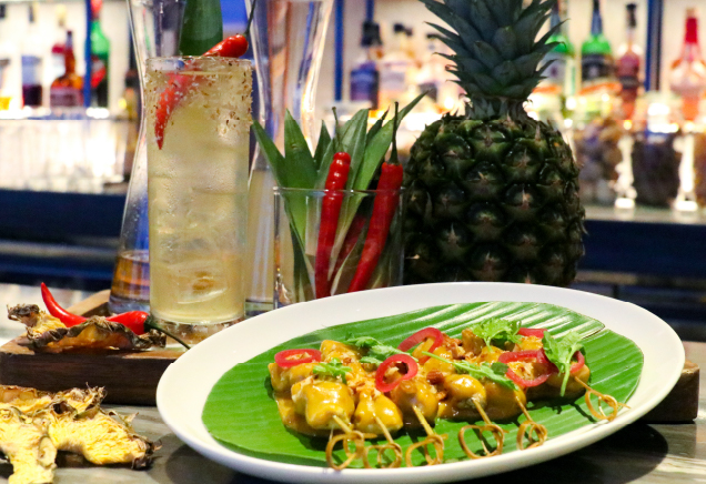 A plate of authentic Malaysian chicken satay, chilled laksa cocktail and pineapple fruit on the table.