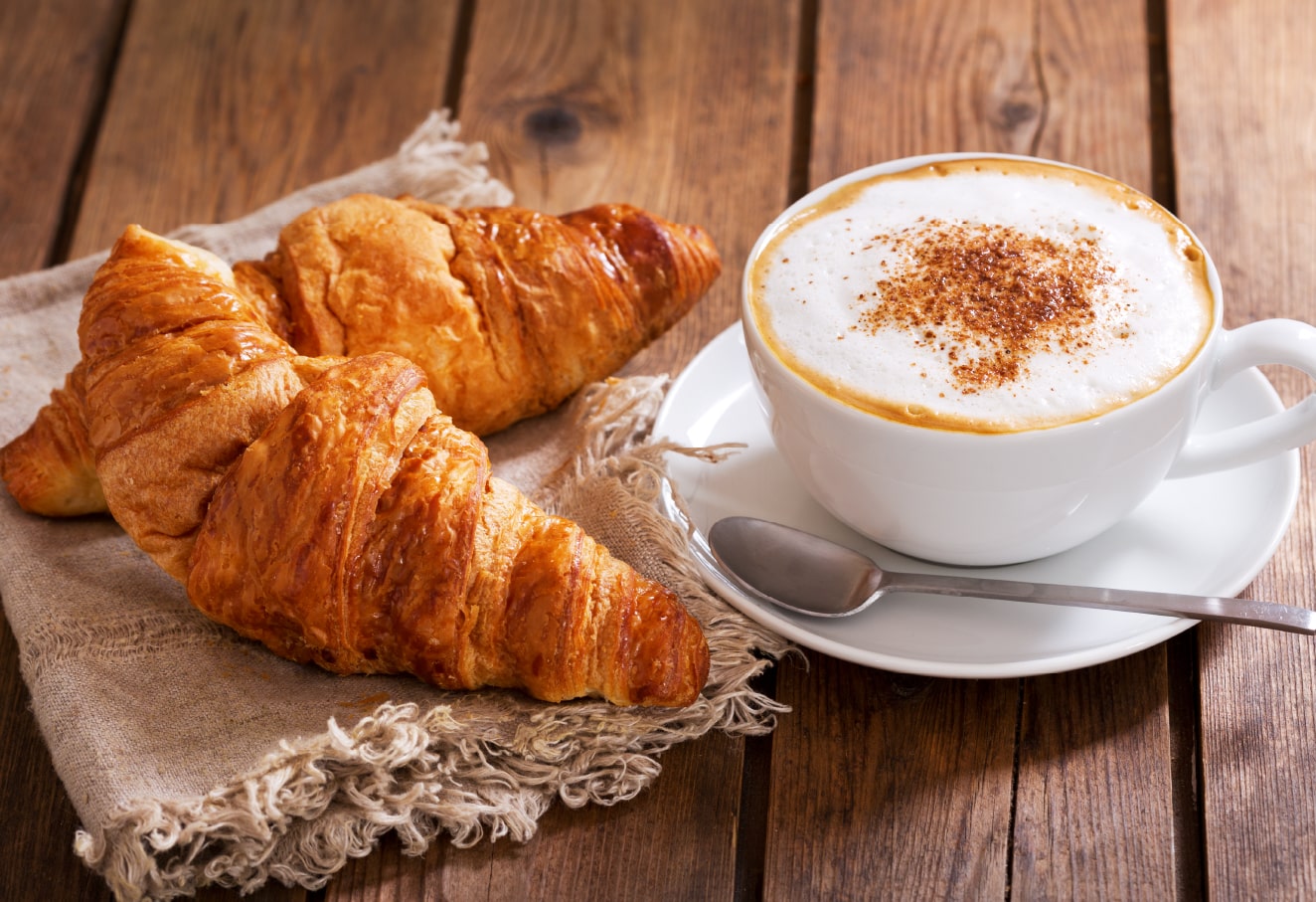 The photo shows two pieces of croissant and a cup of coffee.