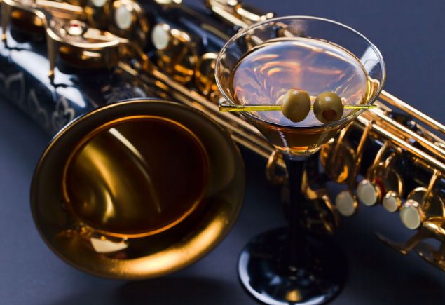 A glass of martini with a trumpet on the table.