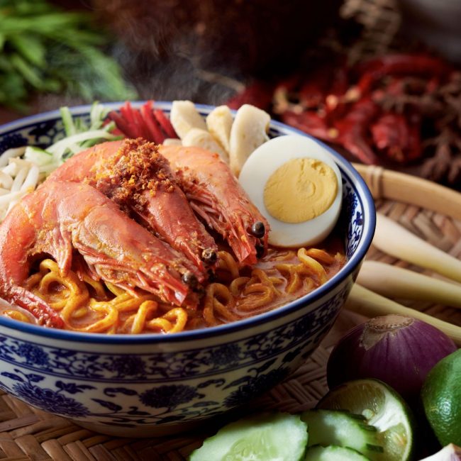 A bowl of authentic spicy curry noodles with prawns, eggs, fishcake and spices.  