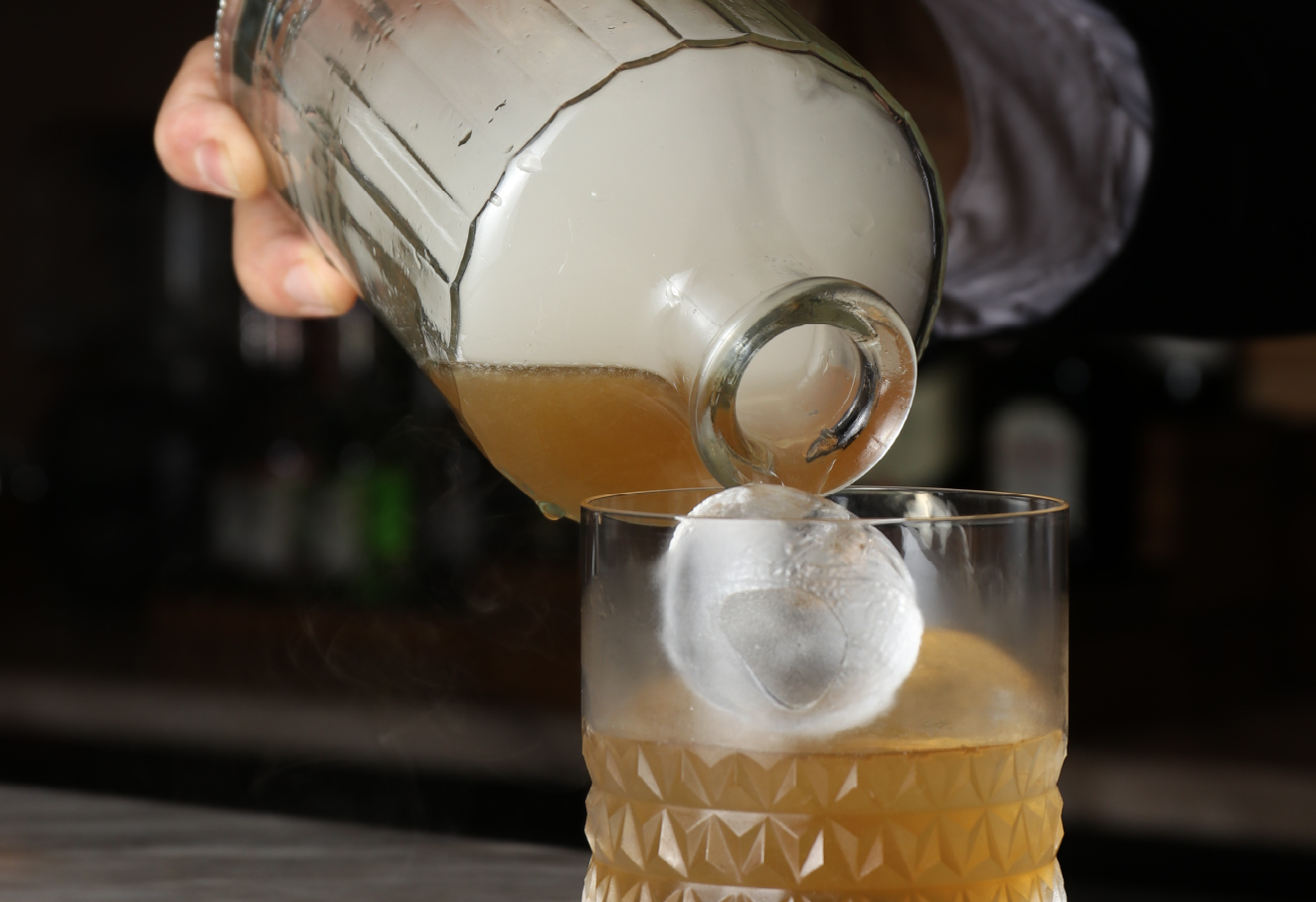 A person is pouring alcoholic drinks in a glass.