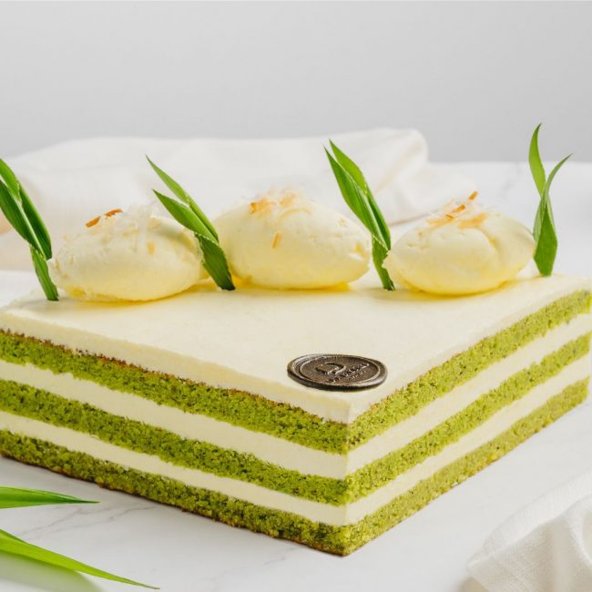 A whole cake of Pandan Onde-Onde cake decorated with pandan leaves and cream.