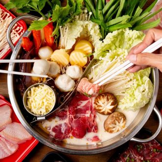 A pot of hotpot with two different soups. The ingredients are being cooked in the pot.