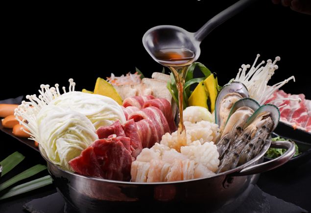 A pot of hotpot with varius meat and seafood.
