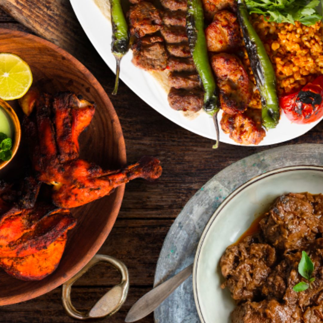 Three plates of Asian dishes such as Tandoori Chicken, Ayam Rendang and Lamb on the table.