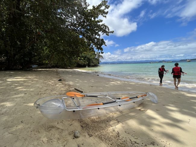 Beach side with a transparent kayak. One male and one female were walking by the sea.