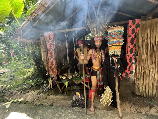 The people of Mari-Mari Cultural Village poses for a photo in front of their hut.