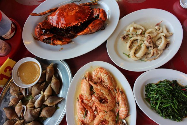 Five plates of Chinese dishes on the table such as crab, squid, butter prawns and more.