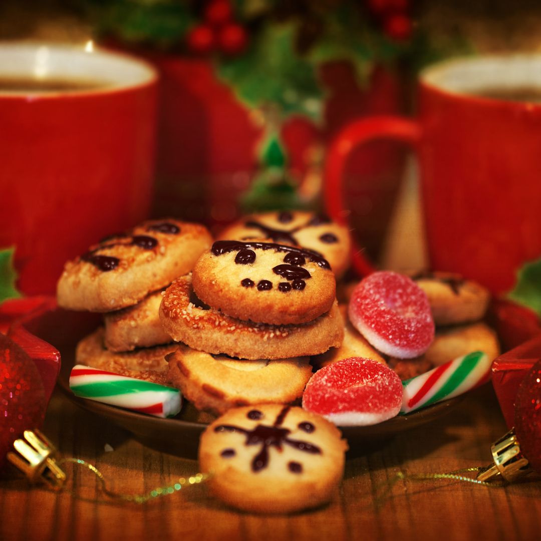 The photo shows a plate of cookies and sweets with two cups of hot beverage at the back.