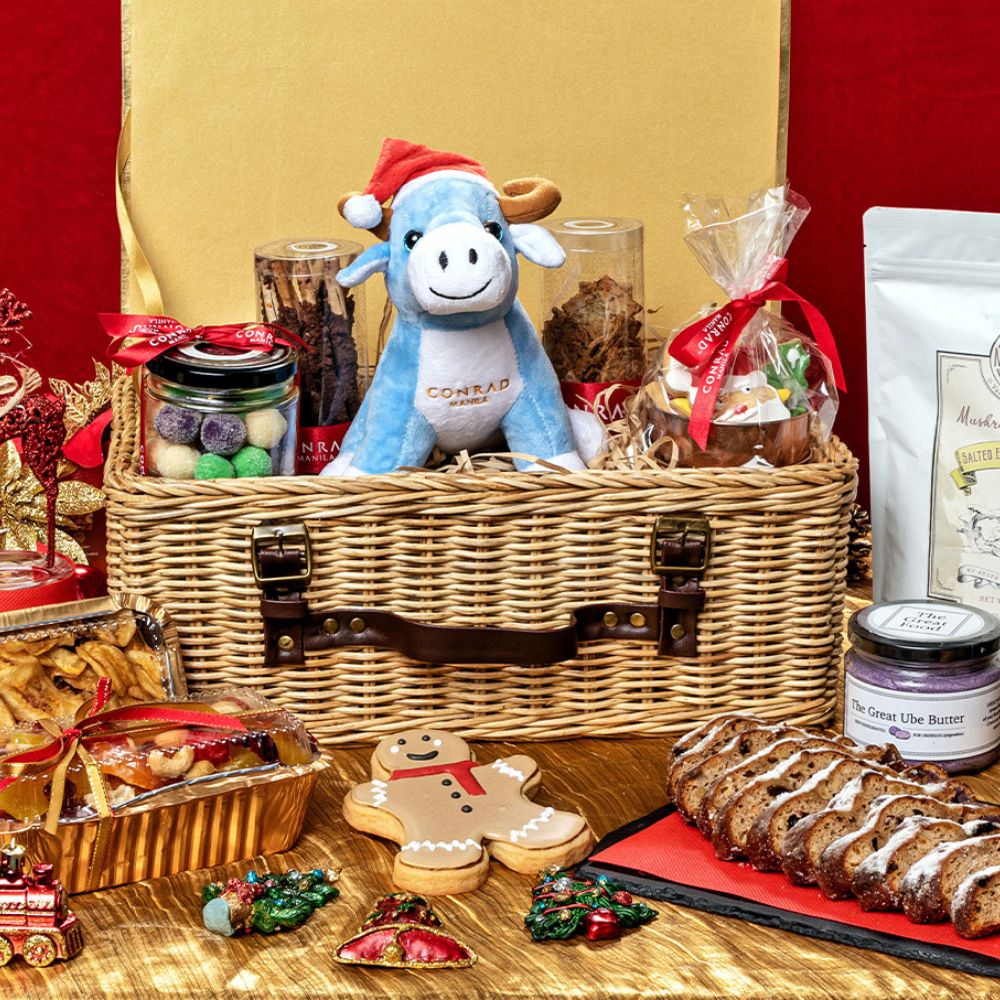 Cornad Manila mascot with festive goodies such as stollen bread, fruit cake, cookies and more