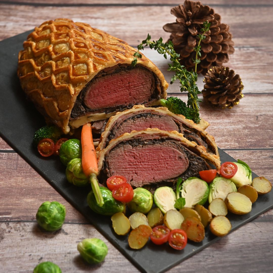 Beef wellington with carrots, tomatoes and brussels sprout.
