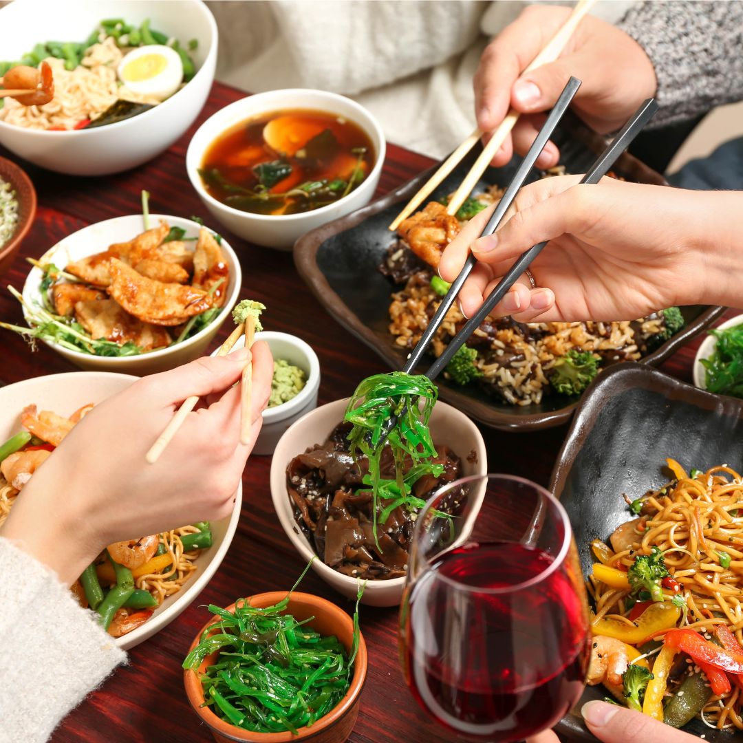 The photo shows a group of 3 people enjoying a variety of Asian cuisine.