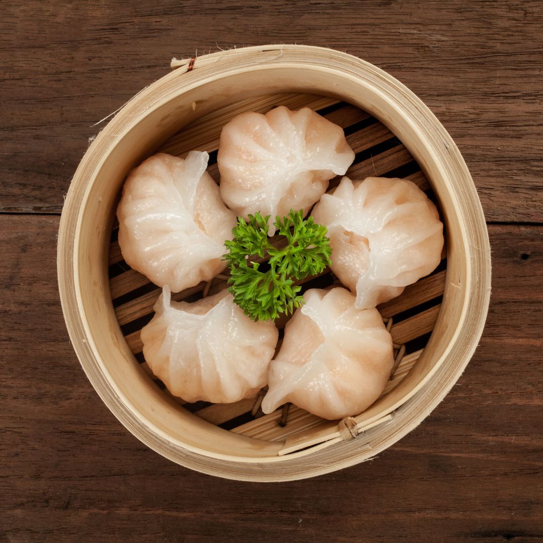 Four pieces of steamed Har Gow in a dim sum bucket.