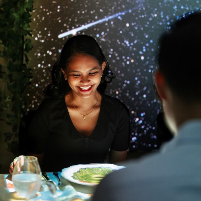 A girl is looking down at the table smiling.