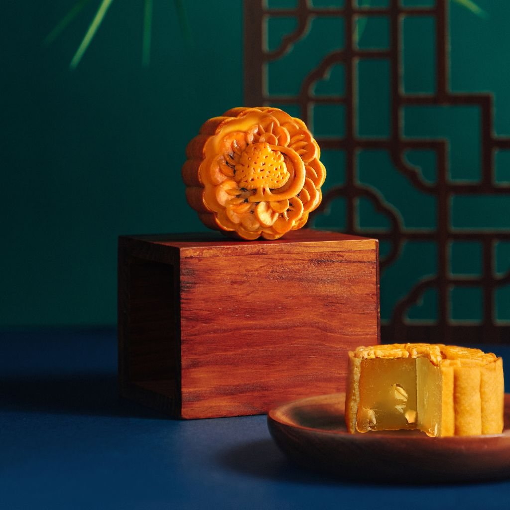 A piece of DoubleTree baked mooncake on a wooden stand. The other mooncake is sliced up on a plate.