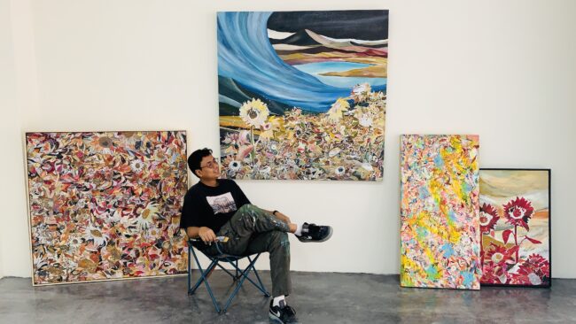 Artist Fadzril Fakaruddin with four of his artwork at the back.